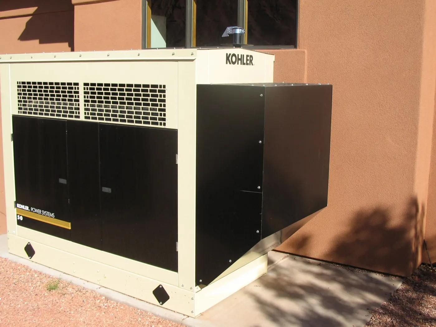 Kohler standby generator on a concrete pad beside a stucco building