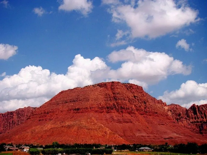 Red Mountain, a red sandstone mesa under a blue sky, with homes and trees along its base